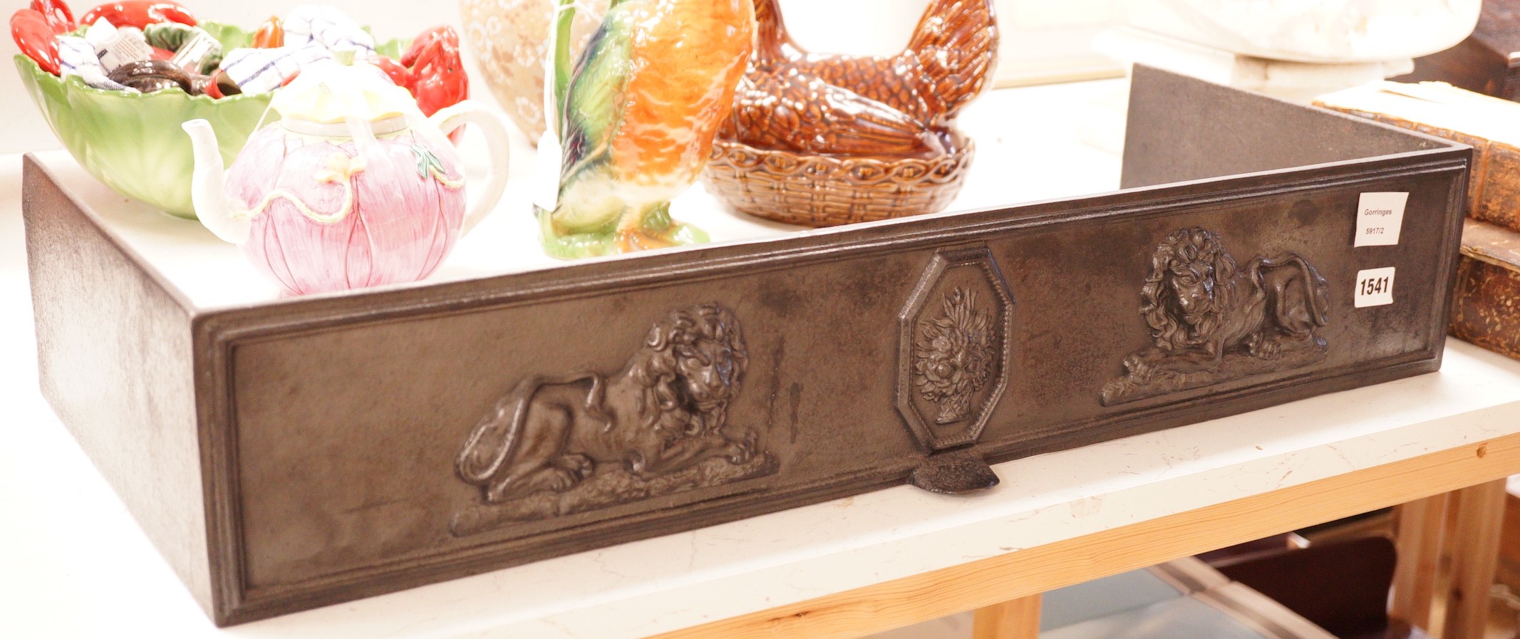 A blackened cast iron fender, of rectangular form decorated with lions, 76.5cm wide, 31cm deep